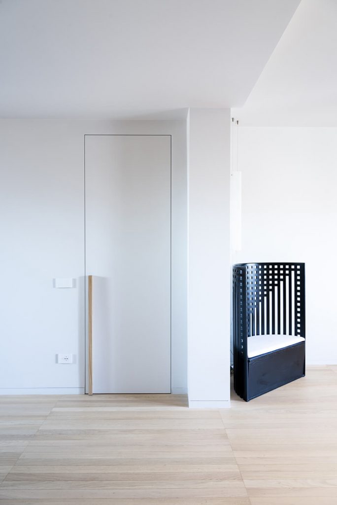 Porta filomuro bianca chiusa di ECLISSE con particolare maniglia adattamento del progettista studio UAIG