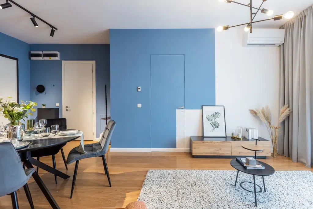 Zona giorno, vista frontale su porta filomuro colorata come la parete in blu e parte in bianco